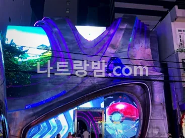 곡면 LED 전광판이 입구를 감싼 알파클럽 건물의 밤 외관