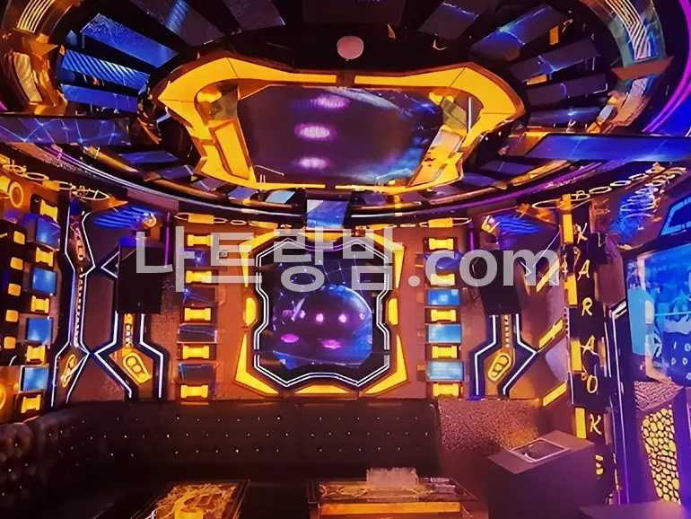 파란 LED 천장과 금색 벽면이 만나는 뉴시티 가라오케 룸