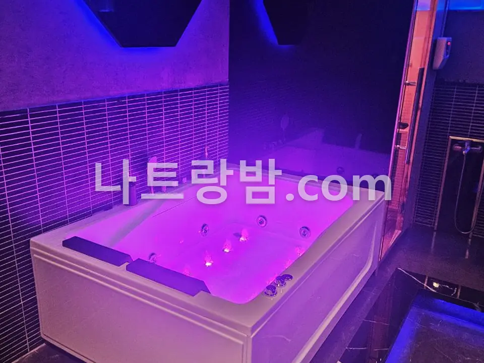 보라 조명 타일 벽 앞에 놓인 나우스파의 안마 욕조