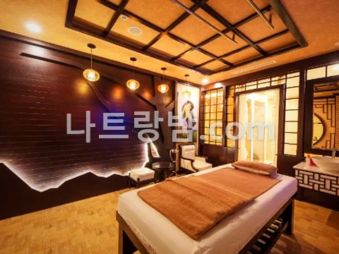 원목 격자 천장 아래 관리 베드를 놓은 쿡테 마사지 객실