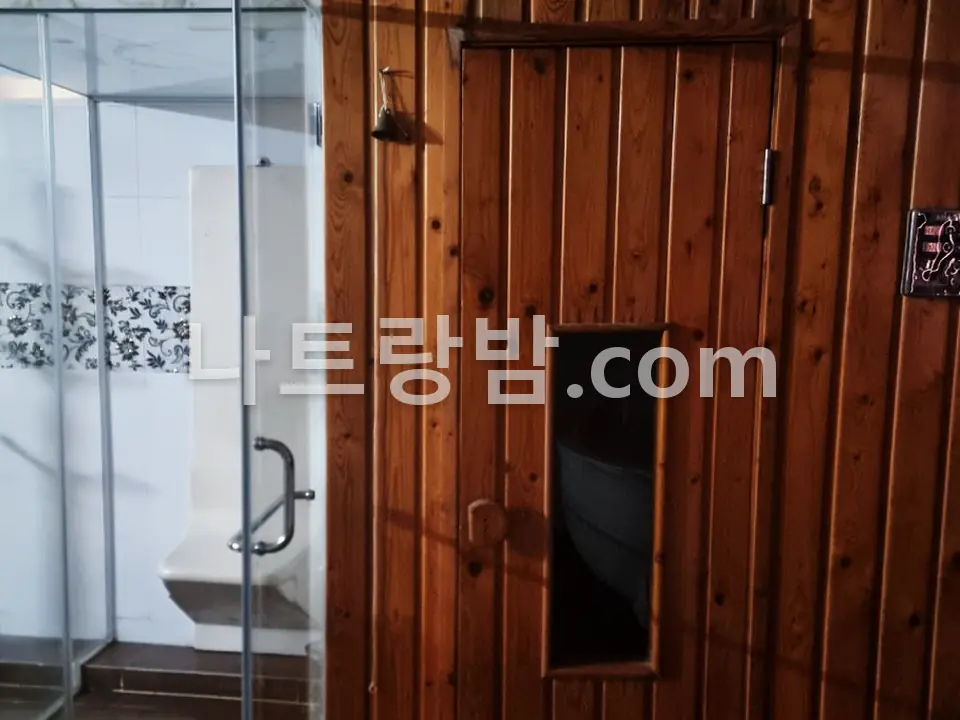 유리 벽 안쪽에 원목 사우나실을 둔 도쿄마사지 공간