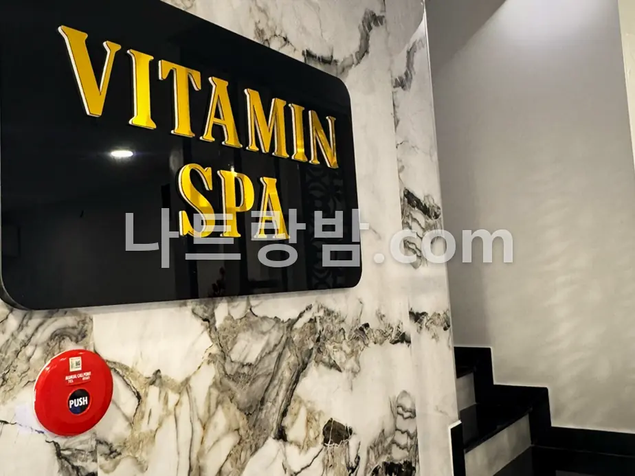 계단 옆 대리석 벽에 금색 상호판을 단 비타민스파 내부 사인